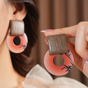 Detailed close-up of retro geometric earrings with wood texture and sunset resin patterns