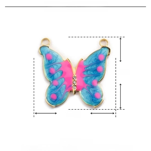 Dettaglio del ciondolo a farfalla in smalto blu e rosa con misure di 24 mm x 24 mm
