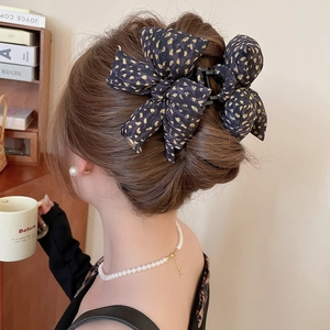 Detail of navy blue leopard print bow hair claw clip styled on a woman's bun hairstyle