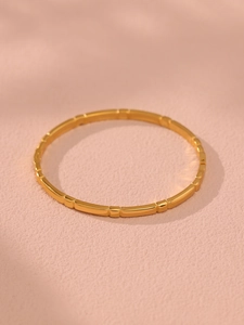 Detailed close-up of a segmented 18K gold geometric bangle with a sleek metallic finish