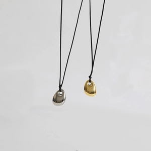 Detailed close-up of polished gold and silver bean pendants on black cord necklaces