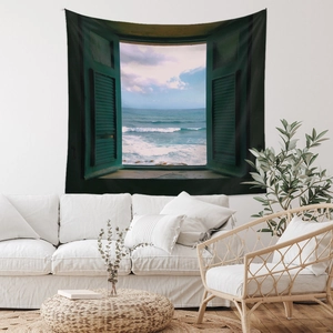 Bohemian tapestry featuring a scenic ocean window view hung above a white sofa