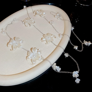 Detail of silver chain with white acrylic flowers and pearls on a white tray