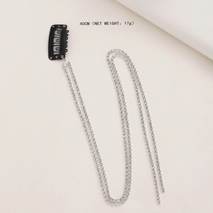 Macro detail of a 40cm silver rhinestone hair chain with black BB clip on white background