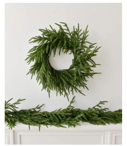 Close-up of realistic green PE Norfolk pine wreath and garland set on a white mantel