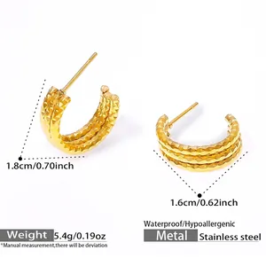 Macro detail of triple-layered gold C-shape earrings showing textured diamond-cut surface