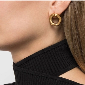 Close-up of irregular 18K gold stainless steel lava earrings worn on a model