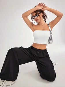 Detail of white knit crop top paired with black drawstring cargo trousers and silver bag