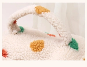 Close-up of white sherpa makeup bag featuring colorful plush polka dots and a soft texture