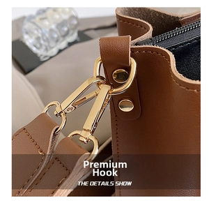 Close-up of golden metal hook and neat stitching on brown leather shoulder strap