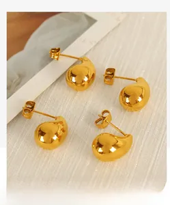 Detailed close-up of polished 18K gold-plated teardrop earrings on elegant white fabric