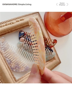 Detail of mini acetate hair combs featuring marble patterns and ergonomic crescent shape