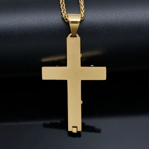 Macro shot of a golden stainless steel cross pendant necklace on a dark reflective surface