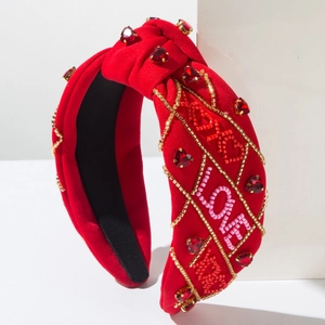 Dettaglio di perline LOVE cucite a mano e strass a cuore rubino sulla fascia rossa