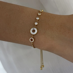 Detail of adjustable gold bracelet featuring white shell inlay and sparkling zircon charms