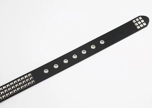 Close-up of black punk belt featuring silver square metal studs and reinforced eyelets