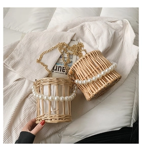 Detailed top view of woven straw bucket bag with pearl handle and golden chain strap