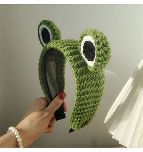 Close-up of knit frog headband showing detailed green yarn texture and big cartoon eyes