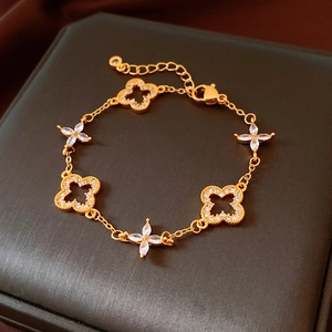Detailed close-up of 24K gold plated clover bracelet with pave crystals on jewelry box