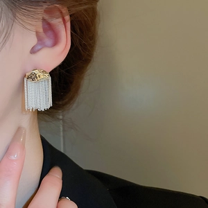 Detail of elegant gold-plated irregular studs with flowing silver chain tassels on ear