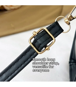 Détail de la bandoulière réglable en cuir noir avec boucle dorée et fermoir mousqueton
