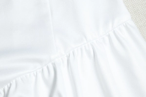 Vue détaillée de la texture du tricot blanc et des coutures à volants sur la robe