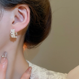 Close-up of pearl crown earrings with lace metal and zircon stones on a model