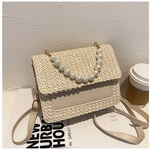 Detailed view of straw-woven crossbody bag with pearl handle and PU leather flap
