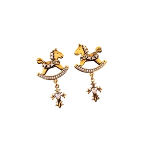 Vintage golden rocking horse earrings with heart zircon pendants on white background