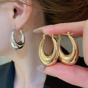 Detailed close-up of chunky C-shaped metallic hoop earrings in gold and silver finish