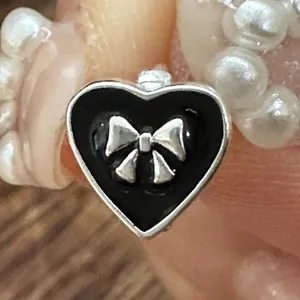 Macro view of a 925 silver heart earring with black enamel and a small bow detail