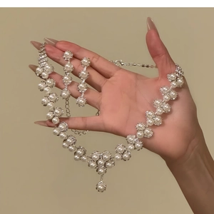 Close-up of pearl necklace and flower earrings set with small diamonds and silver base