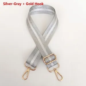 Close-up of adjustable silver-grey nylon bag strap with gold hooks and stripe texture