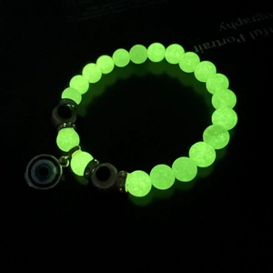 Detailed macro view of glowing green beads and evil eye charm on luminous bracelet