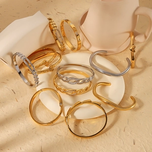 Mix of 18K gold and silver stainless steel bangles with textured patterns and heart motifs