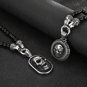 Close-up of gothic skull necklaces featuring black onyx beads and silver steel pendants