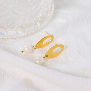 Minimalist gold titanium steel oval pearl earrings on elegant white textured fabric