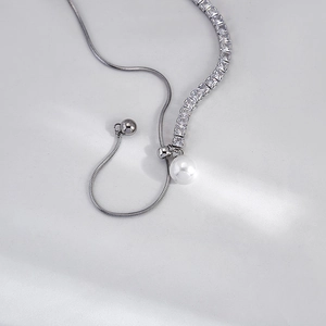 Close-up of silver snake chain necklace with zircon stones and a round white pearl