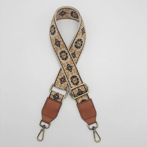Close-up of ethnic woven pattern canvas strap with bronze metal hooks and leather ends