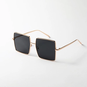 Detailed side view of vintage rectangular sunglasses with gold metal frame and black lenses