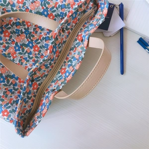 Vista dall'alto della borsa tote in cotone floreale con manici in pelle e zip