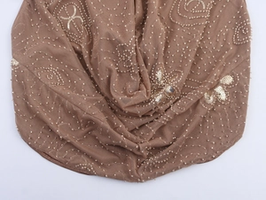 Detailed close-up of brown mesh fabric with hand-sewn beads and sequins floral pattern