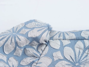Makroaufnahme von blauem Jacquard-Stoff mit silbernem Blumenmuster und feinen Nähten