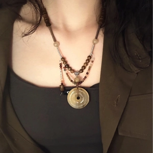 Ethnic multilayer beaded necklace with round jade stone pendant on green garment