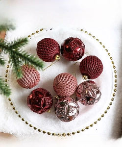 Close-up of assorted red and champagne Christmas ornaments on a decorative glass tray