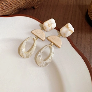 Close-up of geometric resin drop earrings featuring marble texture and vintage design