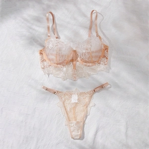 Detailed flat lay of beige lace embroidery bra and panty set on soft white fabric