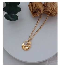 Gros plan d'un pendentif tulipe doré sur chaîne Figaro avec décoration florale élégante