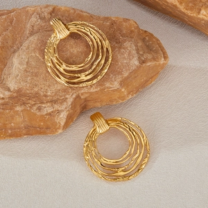 Detailed view of gold multi-layer spiral textured hoop earrings on a stone surface