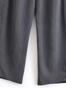 Détail du pantalon de costume gris à rayures montrant la texture tissée et le motif